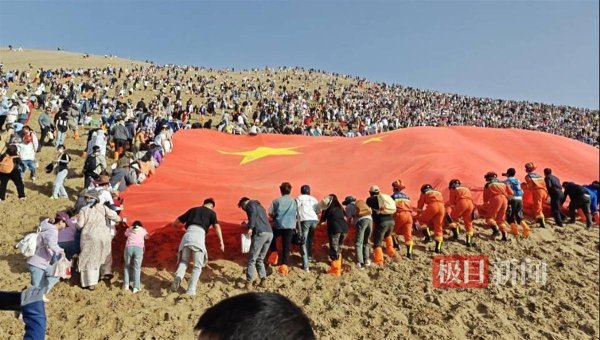 涨8配资 众人接力将国旗升上鸣沙山，纷纷掸去国旗上的沙子